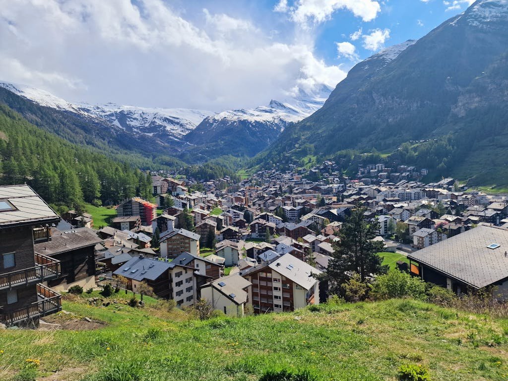 Breathtaking view of Zermatt village surrounded by majestic mountains and lush greenery.