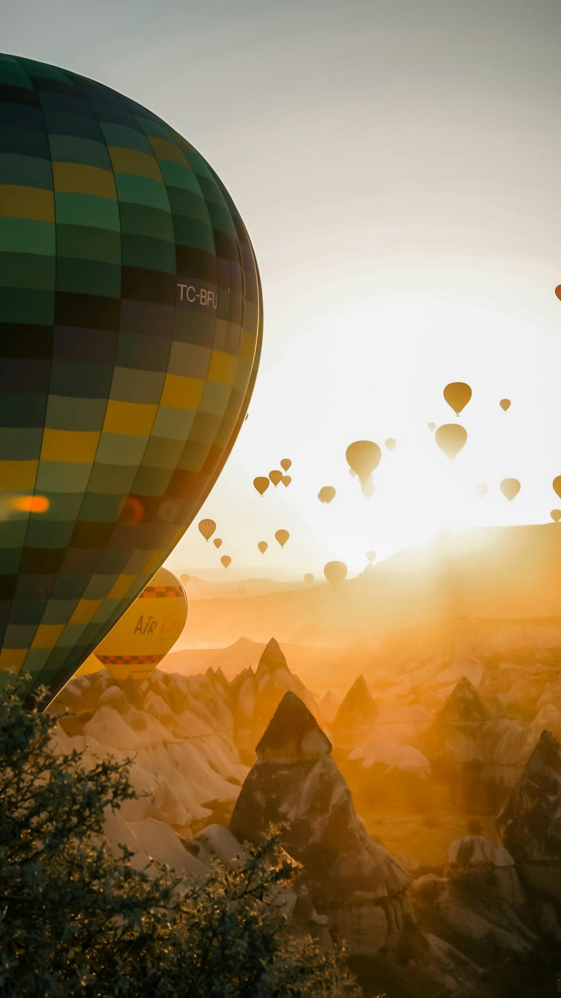 Hot air balloons floating over Cappadocia's rock formations at sunrise, Turkey.
