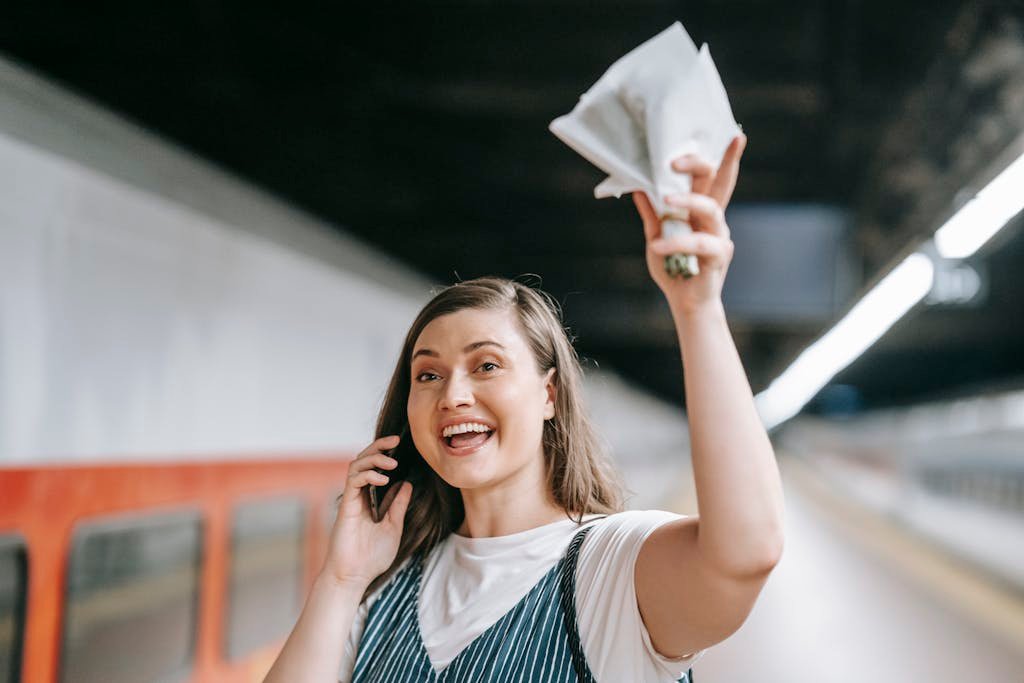 Joyful woman talking and waving at train station, expressing excitement.