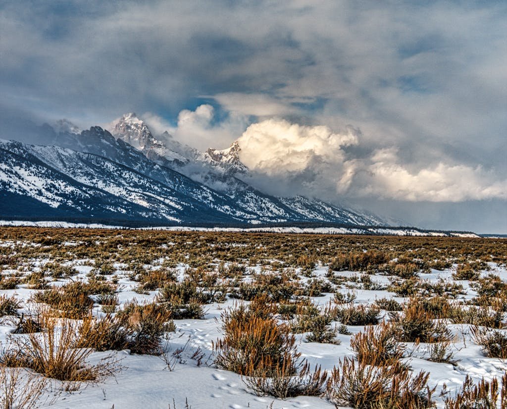 Snow-covered fields beneath the dramatic peaks of the Grand Tetons in Wyoming, USA.
