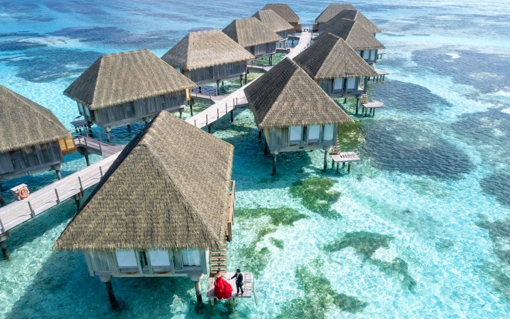 Stunning aerial view of over water bungalows in Fuvahmulah, Maldives, with crystal clear waters.
