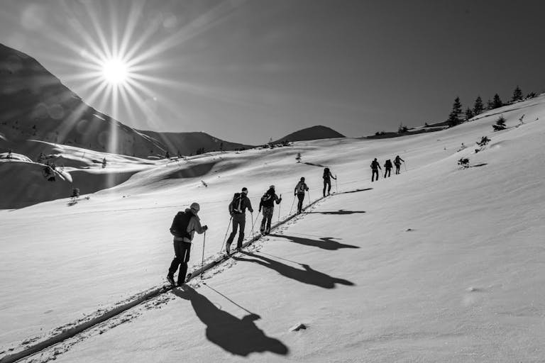 Multiple people on a winter hike in the snow with bright sun burst