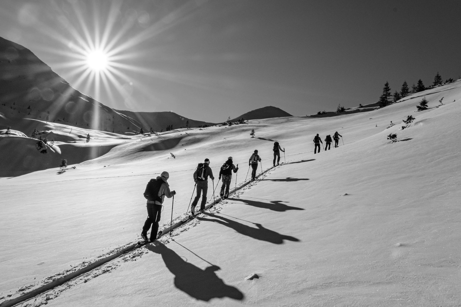 Multiple people on a winter hike in the snow with bright sun burst