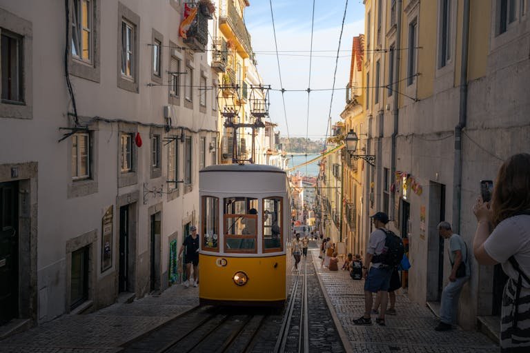 A classic yellow tram navigates a steep street in Lisbon, Portugal, capturing the city's historic charm. Getting Around Lisbon