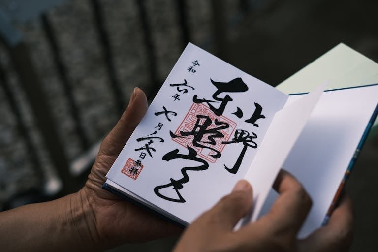 Close-up of hands holding a Japanese calligraphy book, highlighting cultural artistry.