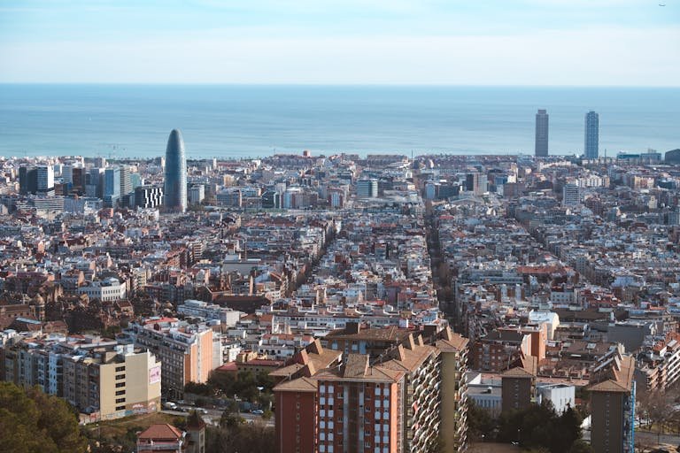 Panoramic aerial shot of Barcelona's cityscape, showcasing the Mediterranean Sea and iconic architecture.