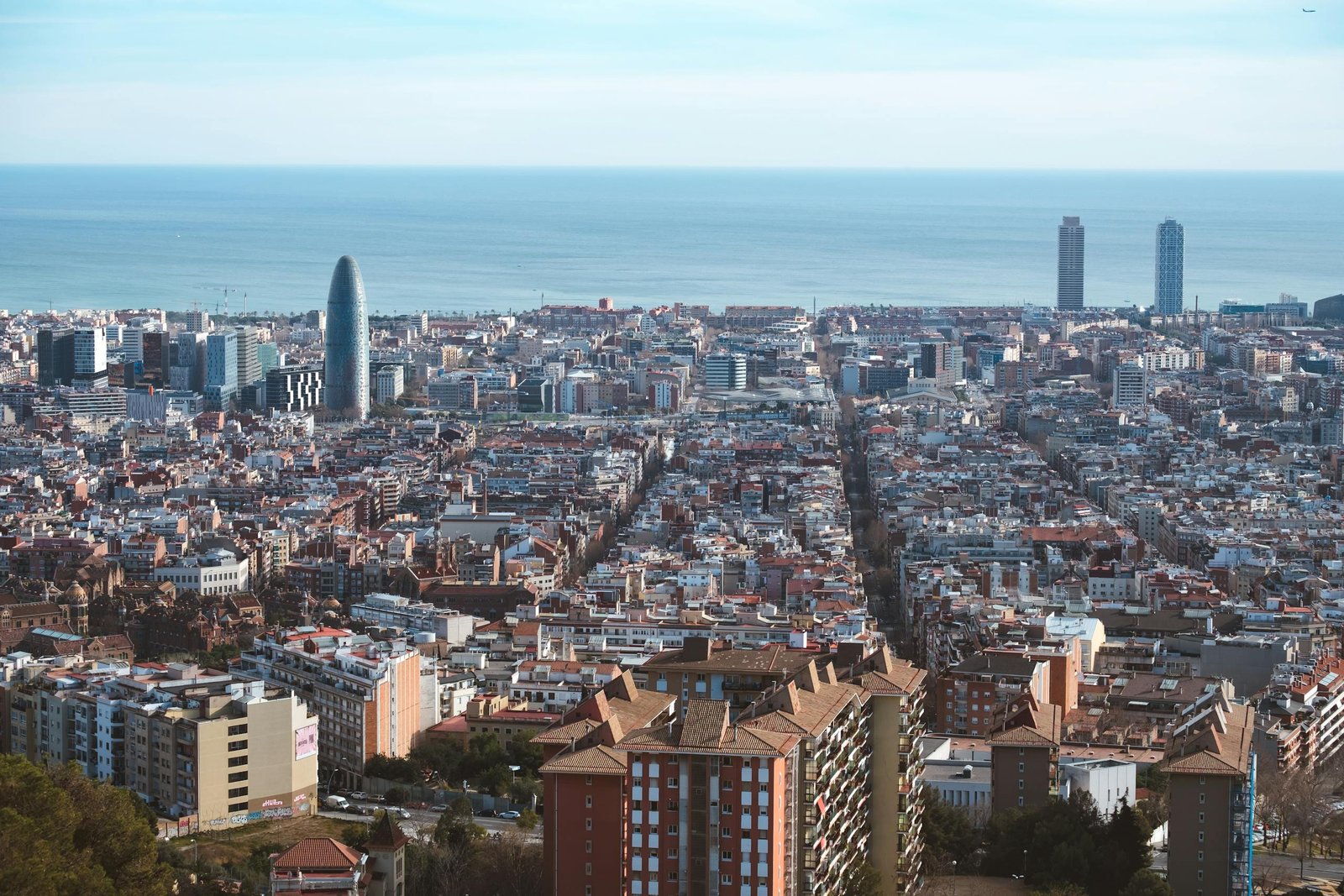 Panoramic aerial shot of Barcelona's cityscape, showcasing the Mediterranean Sea and iconic architecture.