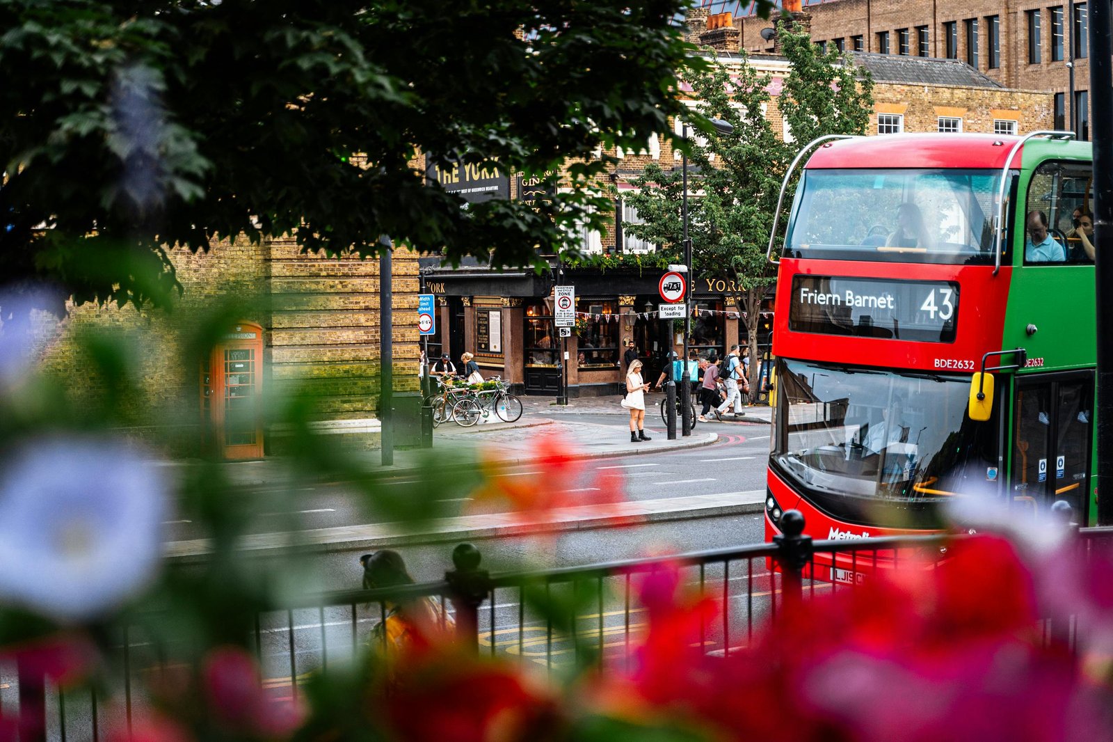 Red double-decker bus in vibrant London street scene with pedestrians and historic architecture. Get Around London