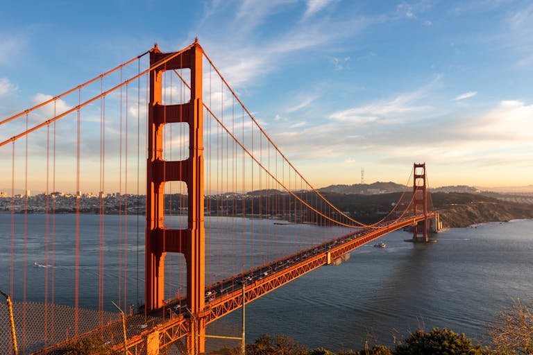 Stunning view of the iconic Golden Gate Bridge at sunset, capturing its vibrant red color against a blue sky.
