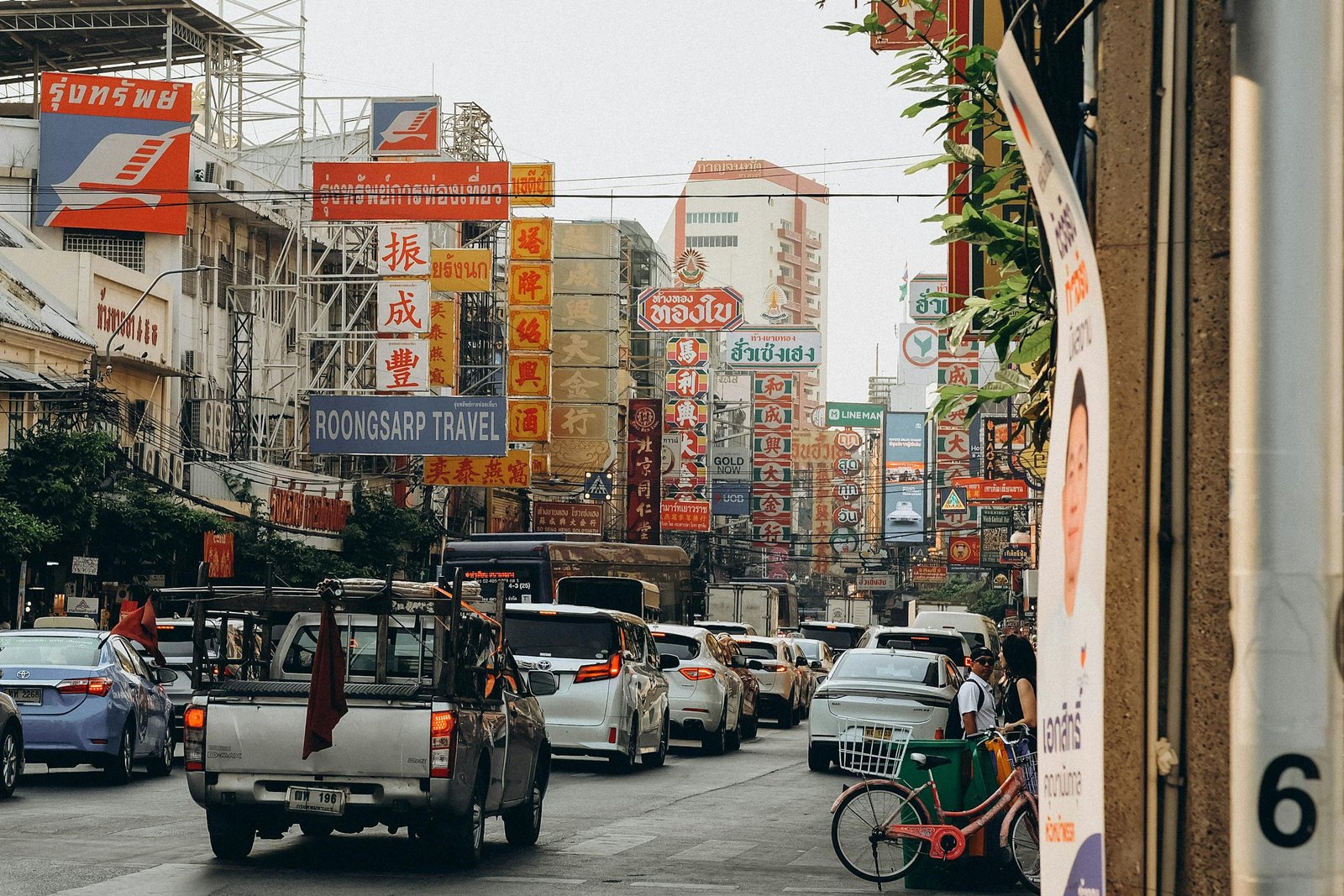Vibrant street view of Bangkok's Chinatown with colorful signs and traffic, showcasing urban life.