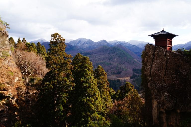 Explore the tranquil beauty of Japan's mountain landscape with a temple and lush greenery.